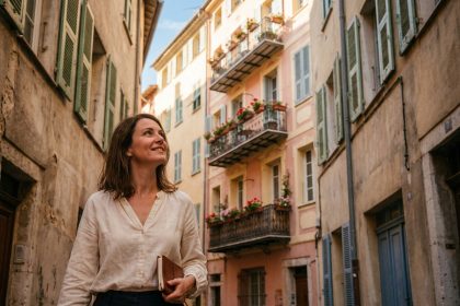 Femme consultant un carnet devant un immeuble aux façades pastel dans le Vieux-Nice, idéal pour illustrer l'achat d'un pied-à-terre à Nice