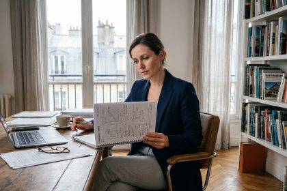 Femme consultant un diagnostic immobilier dans un appartement parisien avec parquet en chevrons et vue sur toits haussmanniens